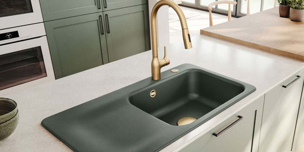 Salbei-färbige Spüle mit goldenem Wasserhahn in einer modernen Küche