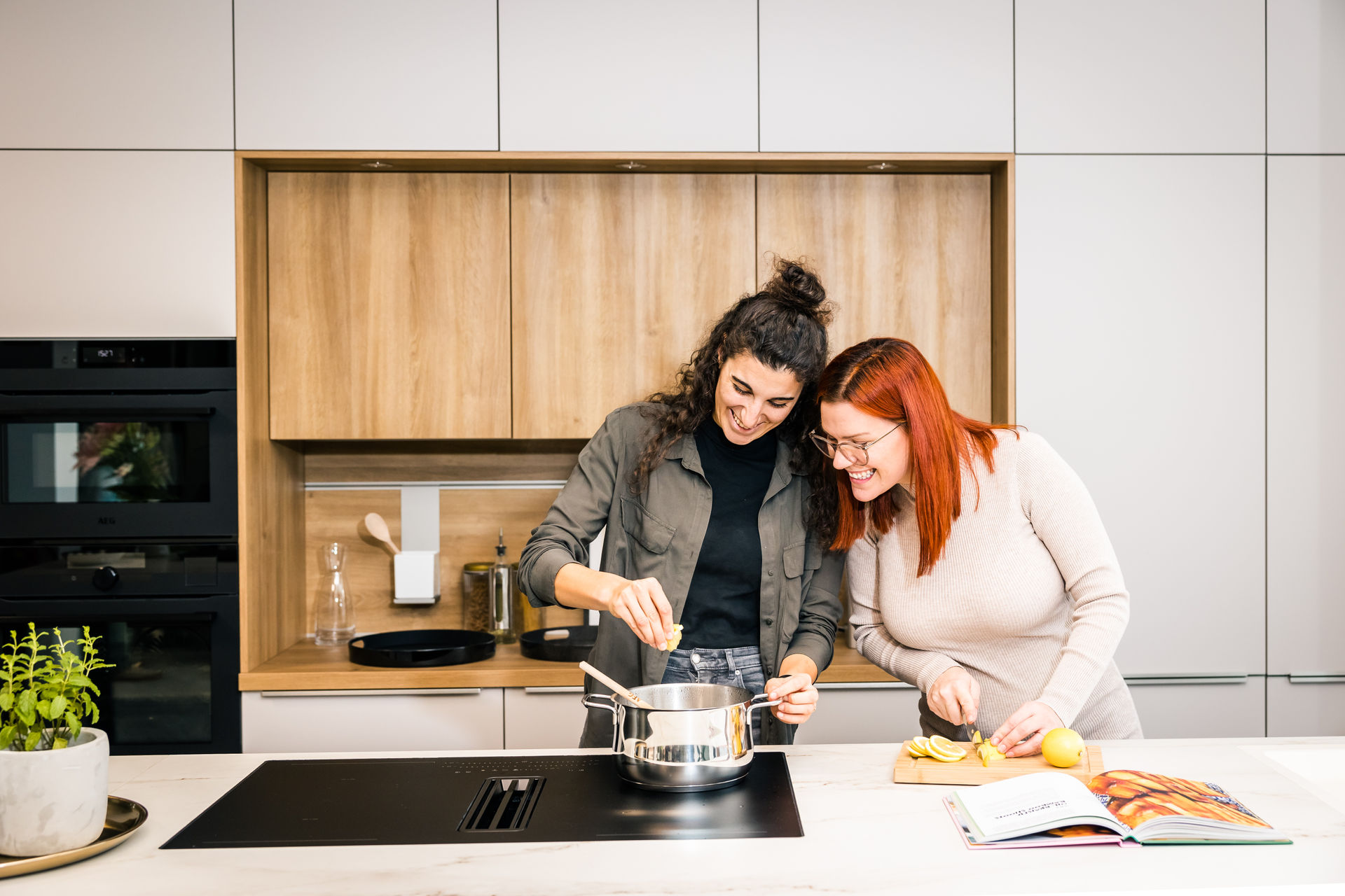 Zwei Frauen stehen in einer hellen, modernen Küche und kochen