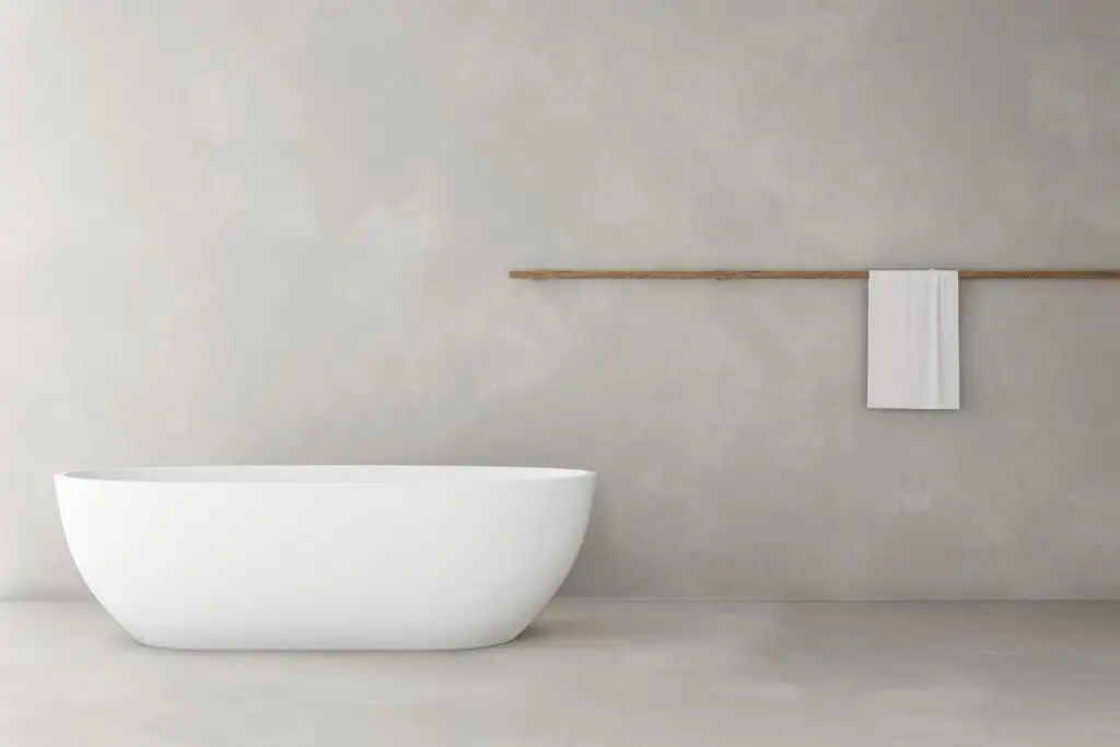 Cleanes Badezimmer mit einer schlichten, weißen Badewanne vor einer grauen Betonwand